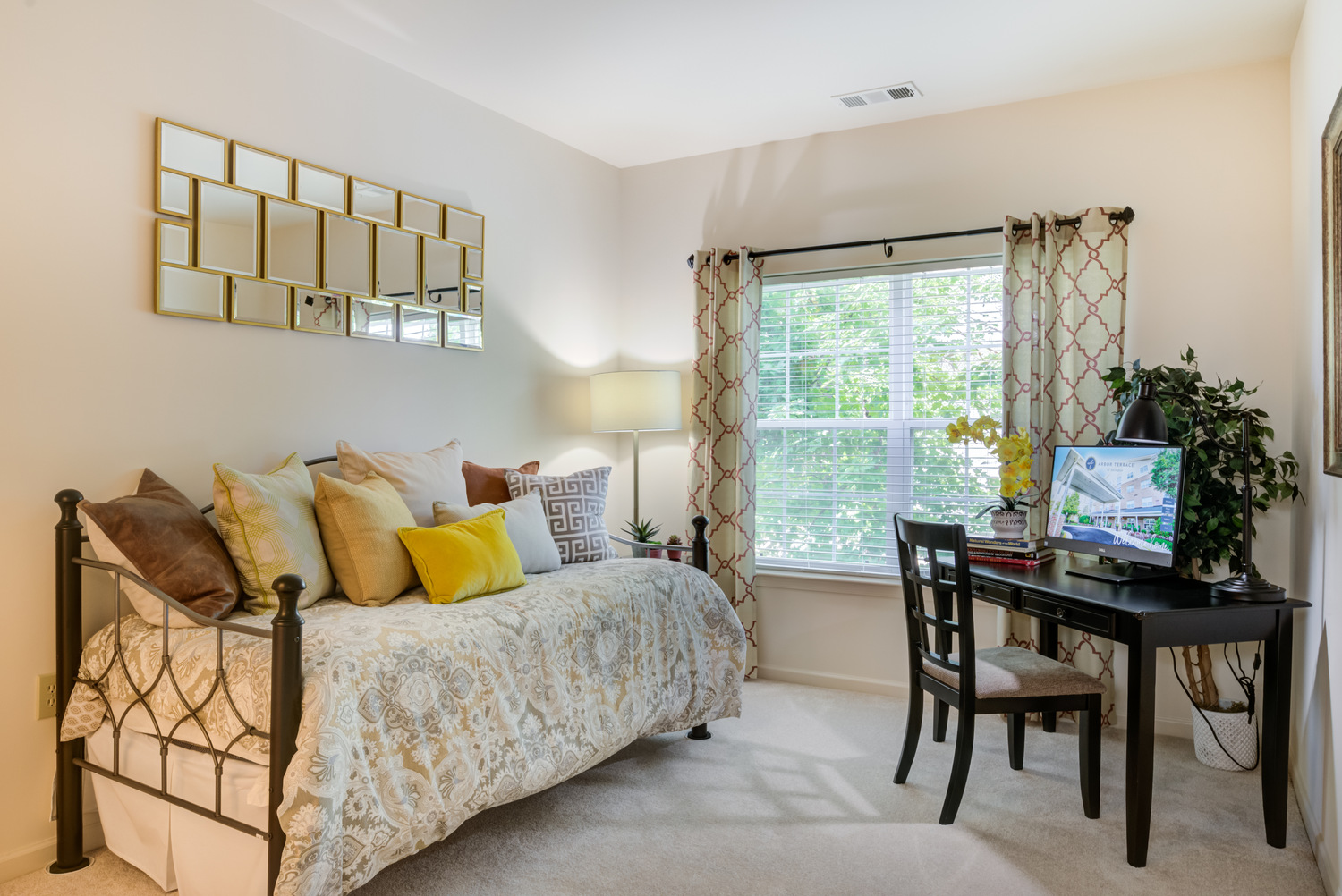 A well-appointed senior apartment at Arbor Terrace Herndon featuring a neatly made bed, warm wood furnishings, and a large window, offering comfortable independent living in Herndon, VA.