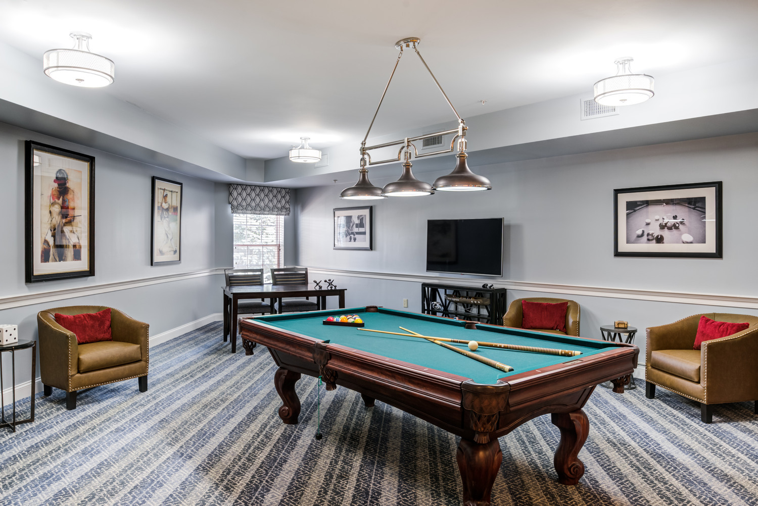 A fun and social game room at Arbor Terrace Herndon featuring a billiards table, comfortable seating, and a wall-mounted TV, perfect for active seniors enjoying independent living in Herndon, VA.