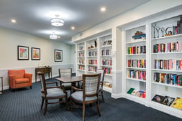 A bright and inviting library at Arbor Terrace Herndon lined with floor-to-ceiling bookshelves, warm seating, and reading tables, perfect for residents enjoying independent senior living in Herndon, VA.