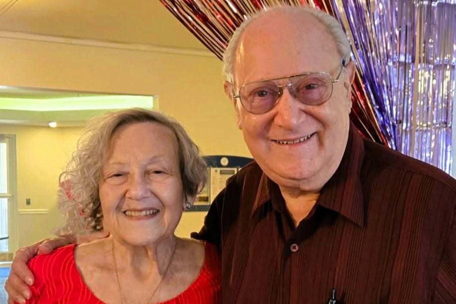 Two residents share a joyful smile at a festive celebration full of sparkle and cheer, capturing the warm community spirit at Arbor Terrace Herndon, a senior living Herndon Virginia community offering vibrant independent living Herndon VA.