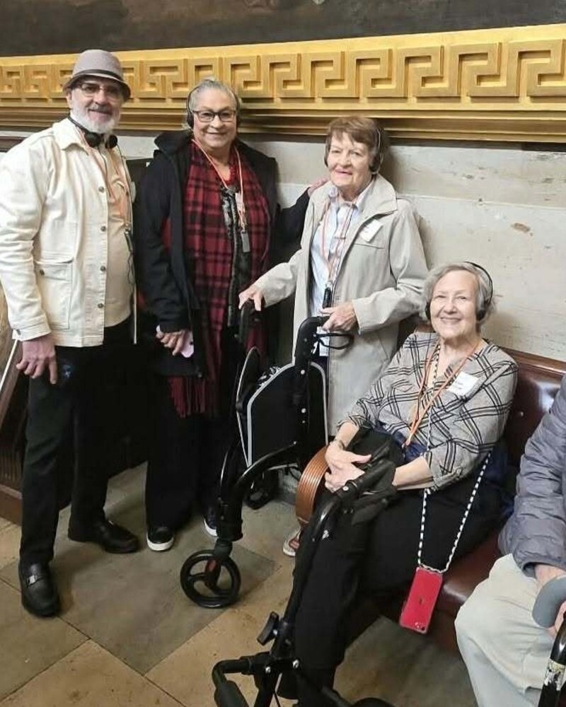 Four residents pose together warmly during an outing in an elegant, gold-trimmed hallway, reflecting the active senior living Herndon VA lifestyle enjoyed at Arbor Terrace Herndon, a vibrant senior living Herndon Virginia community.
