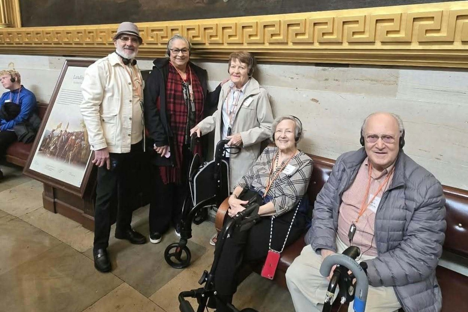 A group of friends poses together during an outing in a beautifully detailed hallway, showcasing the active senior living Herndon VA lifestyle enjoyed at Arbor Terrace Herndon, a vibrant senior living Herndon Virginia community.