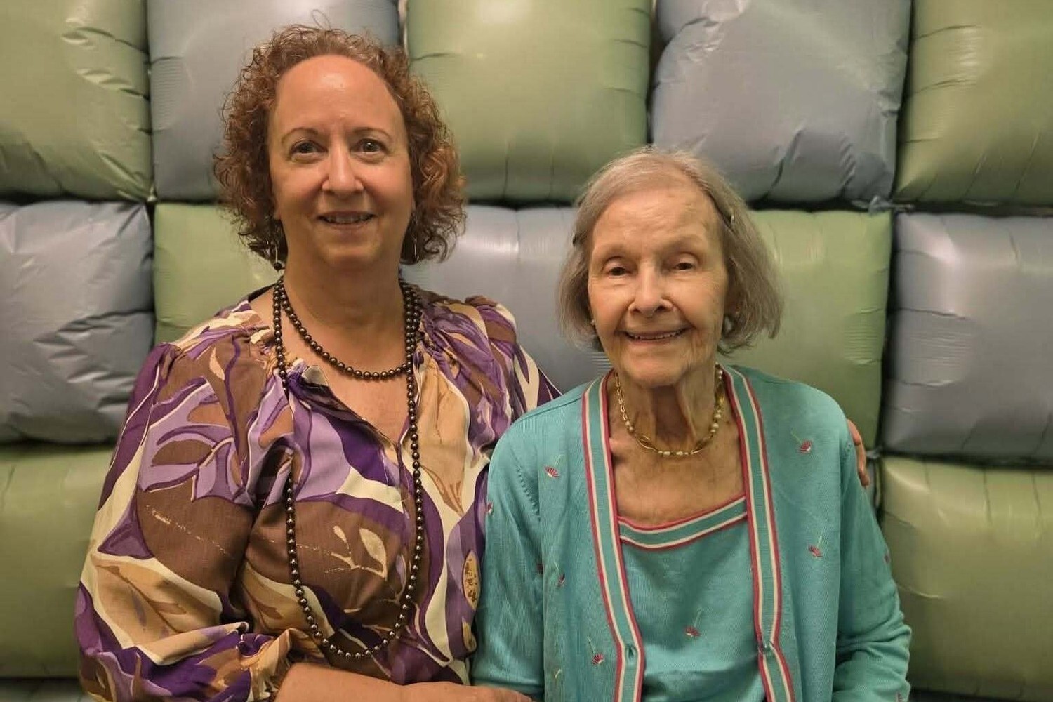 Two smiling women enjoy a warm visit together in a cozy lounge, reflecting the friendly connections built every day at Arbor Terrace Herndon, an independent living Herndon VA community known for its welcoming senior living Herndon Virginia lifestyle.