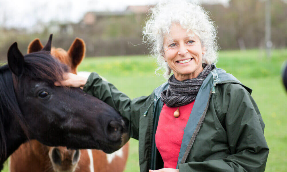 A smiling woman enjoys a close encounter with a horse at Frying Pan Farm Park, highlighting the engaging outdoor activities and local attractions near retirement communities in Herndon, VA.
