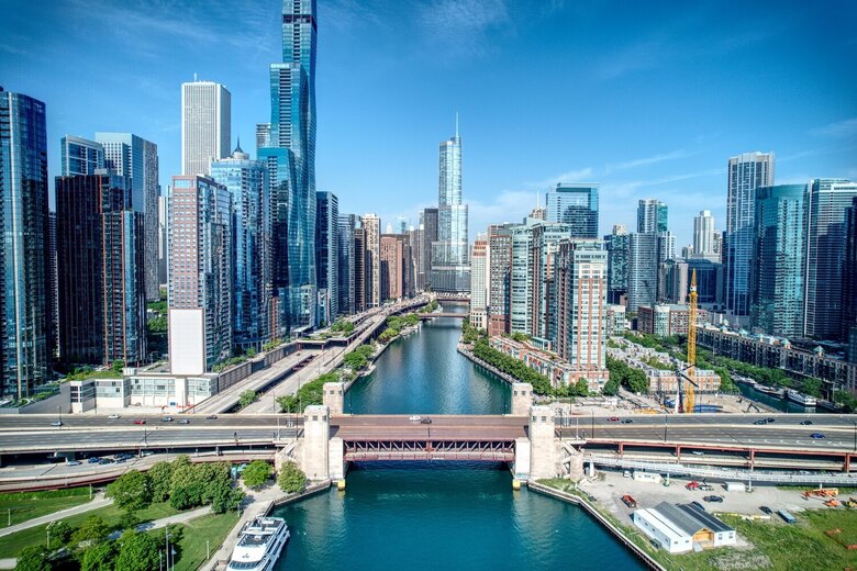 Glass towers and high-rises line a winding river beneath a bright blue sky, a striking city view within easy reach of senior living Highland Park IL and the many senior living resources on Chicago's North Shore.