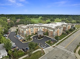 Aerial view of Arbor Terrace Highland Park, a multi-story senior living community in Highland Park, IL, with a circular drive and green space nearby.