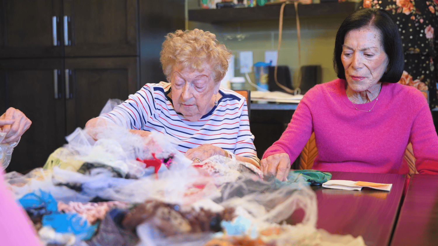 Residents sit together sorting colorful yarn and fabric scraps during a craft activity at our senior living community in Highland Park, IL.