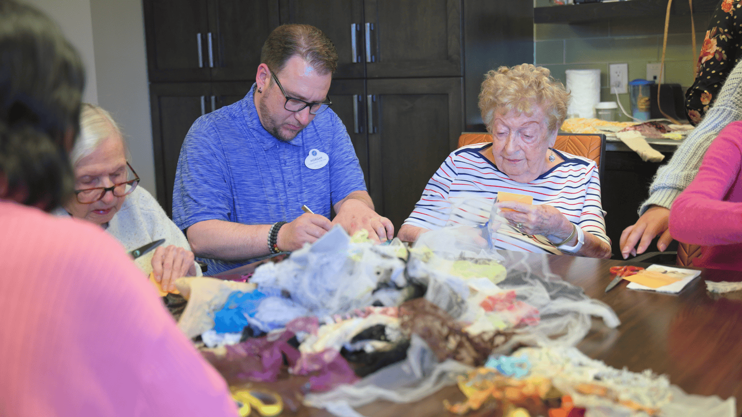 A staff member helps a resident with a fabric craft project at our senior living community in Highland Park, IL, where hands-on activities bring residents together.