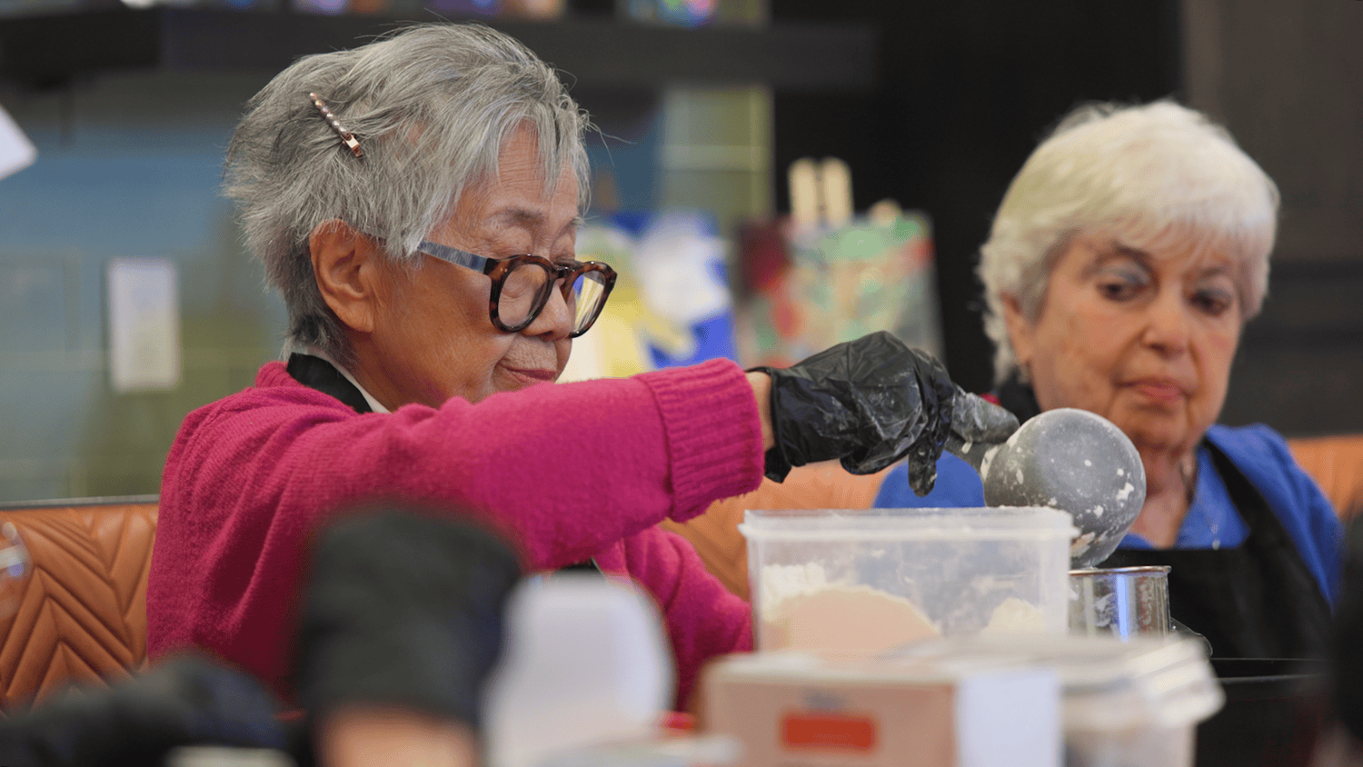 A resident carefully scoops flour during a hands-on baking  activity, part of the active senior lifestyle at our senior living community in Highland Park, IL.