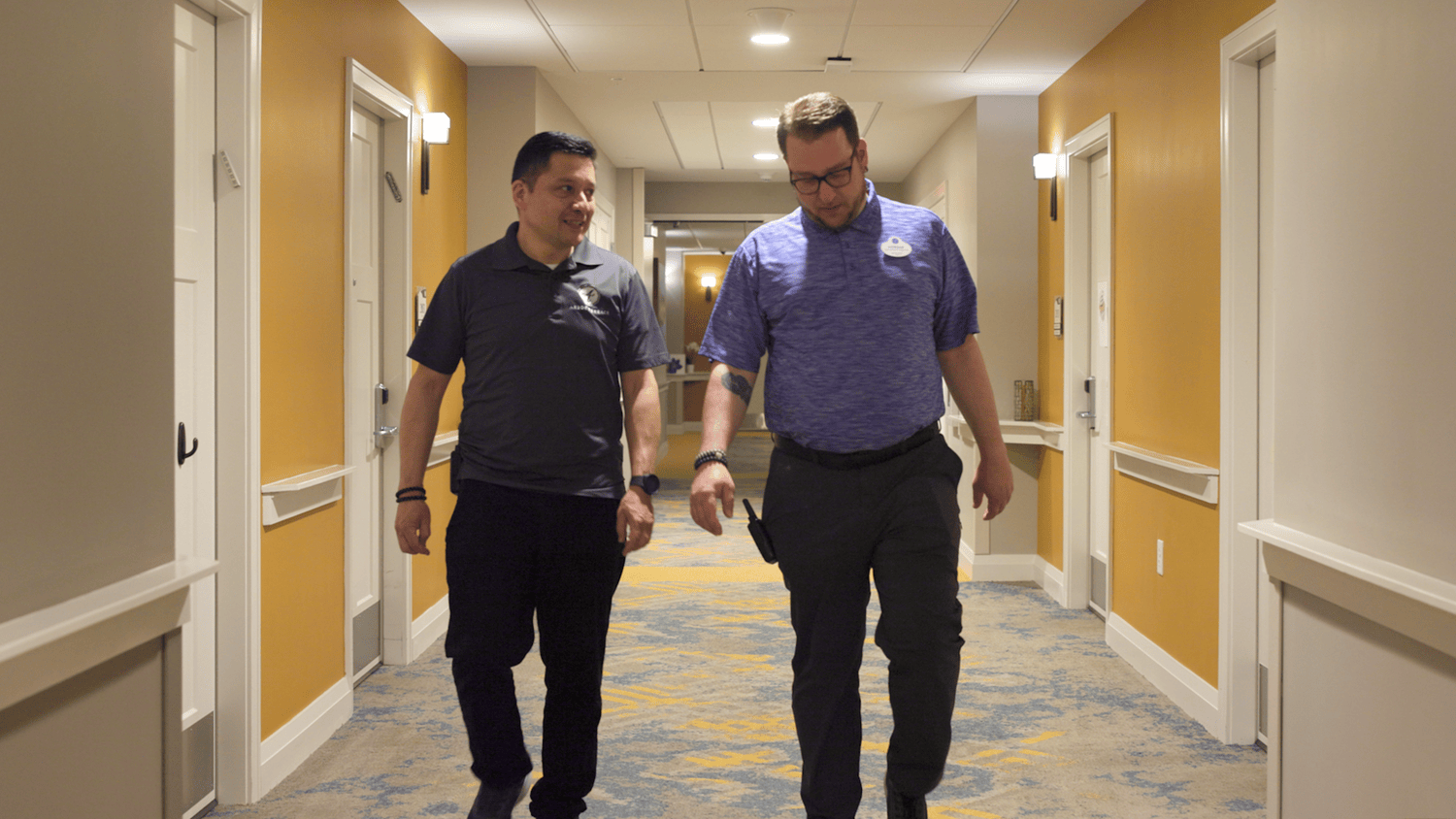 Two staff members walk and chat down a bright hallway at our senior living community in Highland Park, IL.