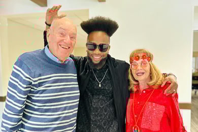 Senior man and woman smiling with team member dressed in 70s fashion
