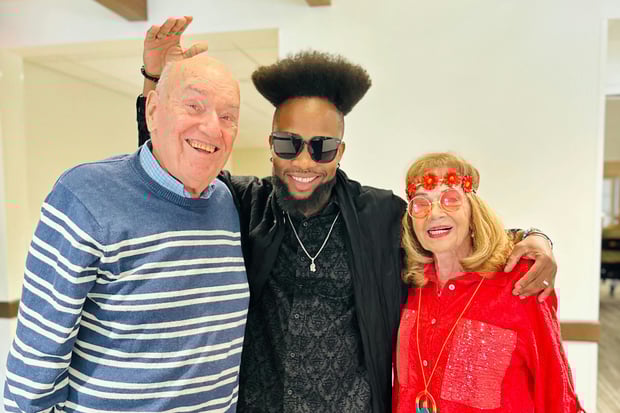 Senior man and woman smiling with team member dressed in 70s fashion