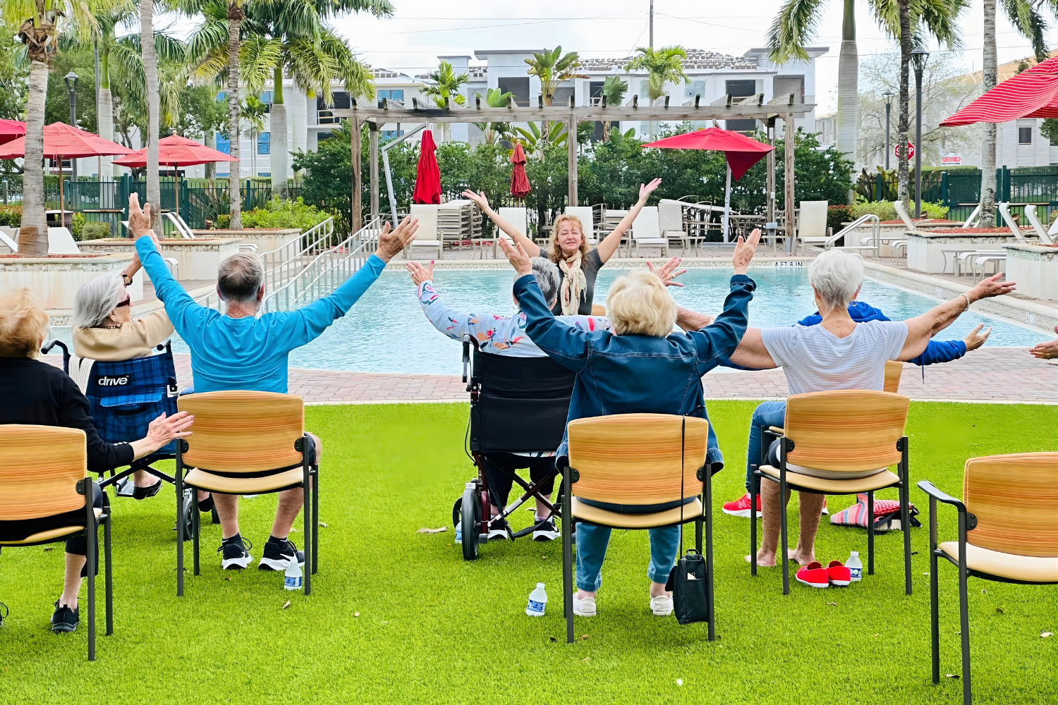 Residents participating in seated yoga in front of the pool