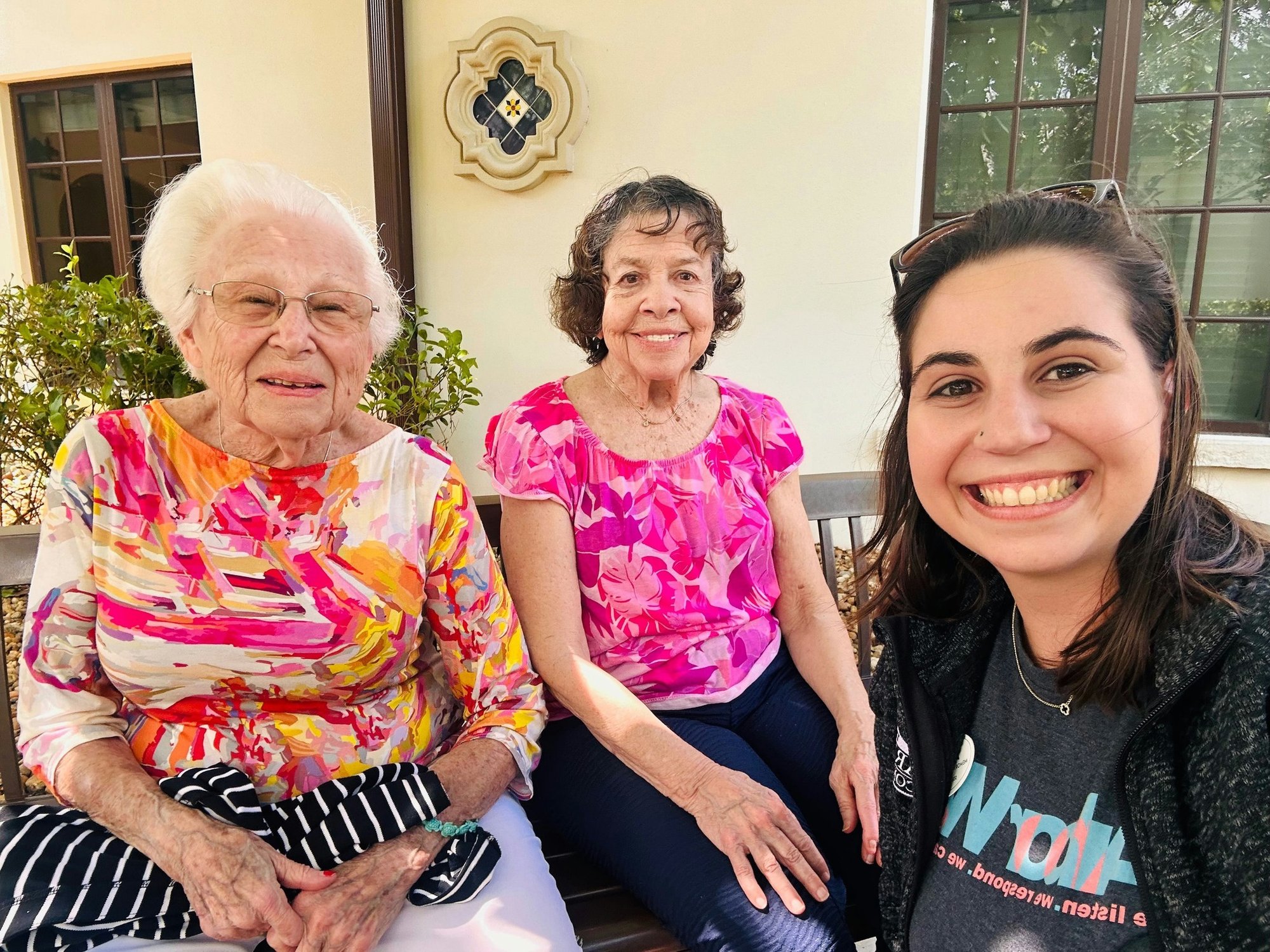 two senior ladies and female staff member take a selfie outdoors