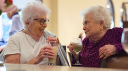 Two senior ladies enjoying their drinks by the dining area bar at the Arbor at Lake Worth