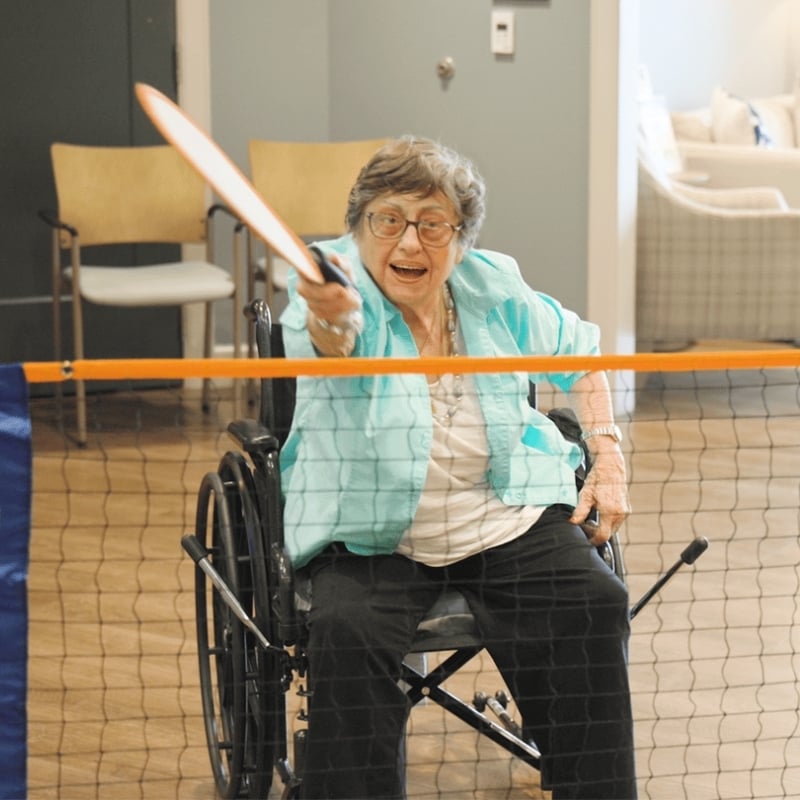 senior resident in wheelchair playing tennis