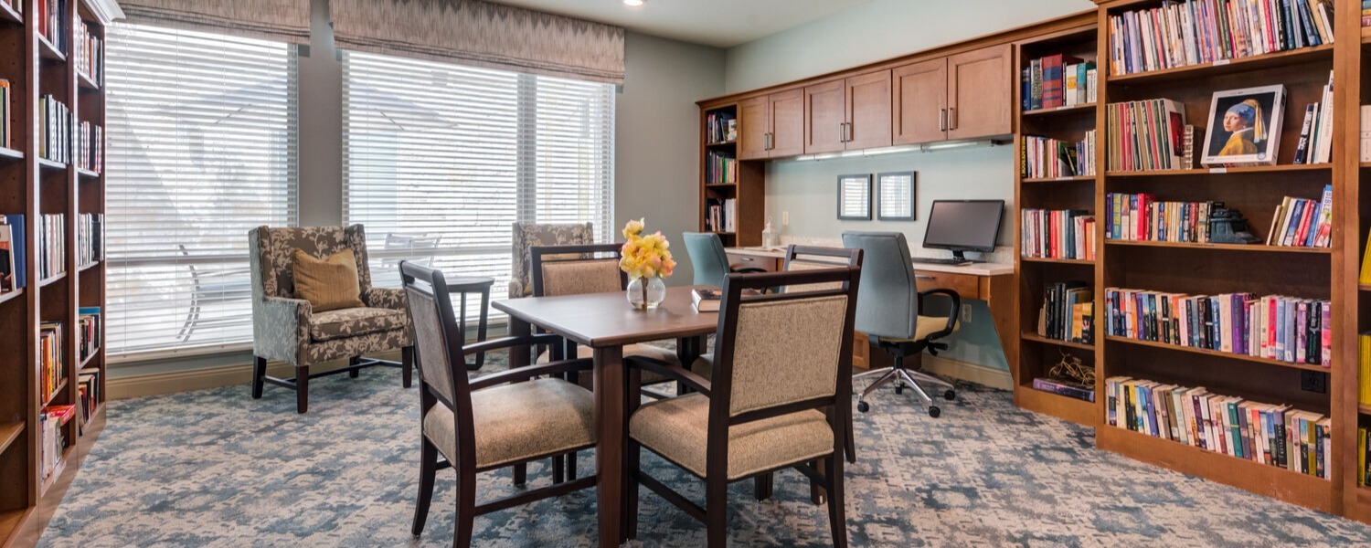 Well-stocked resident library at Arbor Terrace Lakeway TX, offering a quiet retreat with rich wood bookshelves, comfortable chairs, and soft lighting — ideal for reading and reflection at this senior living community.