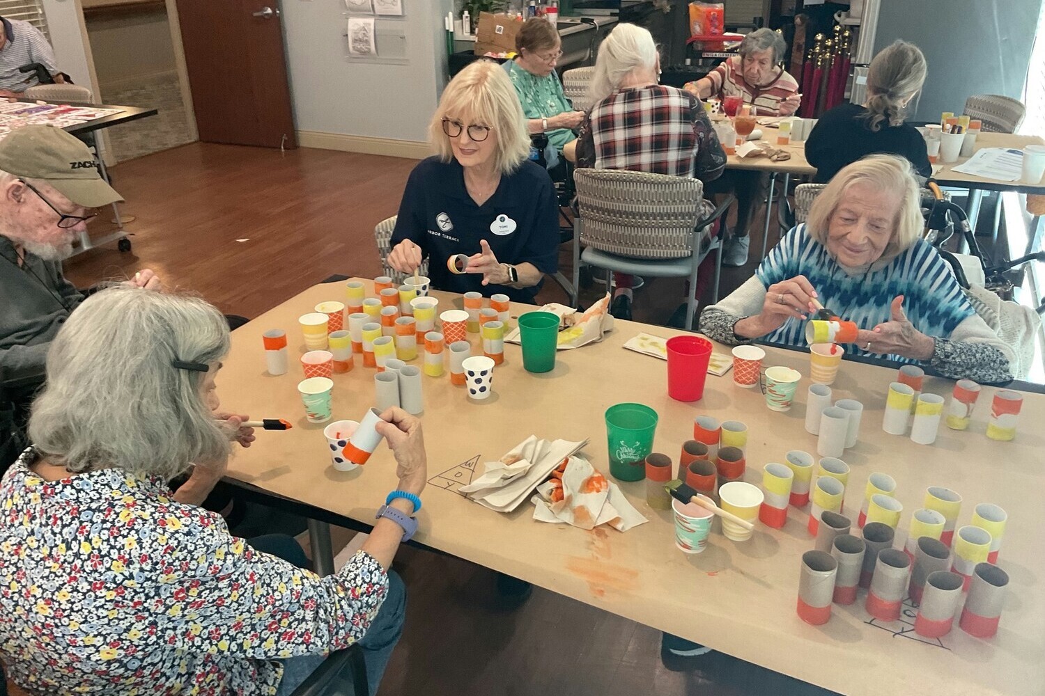 Residents enjoy a vibrant arts and crafts activity around a large table at Arbor Terrace Lakeway TX senior living, with colorful supplies and cups spread out in a lively, creative group setting.