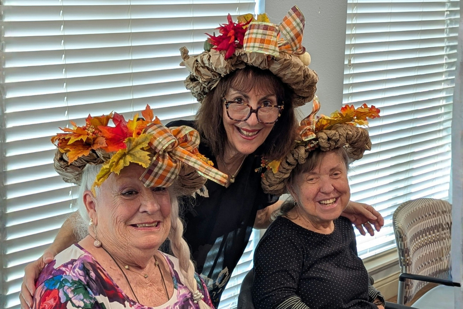 Residents and a staff member show off fun, festive autumn hats at Arbor Terrace Lakeway TX senior living, celebrating the season together in a playful, community-spirited social event.