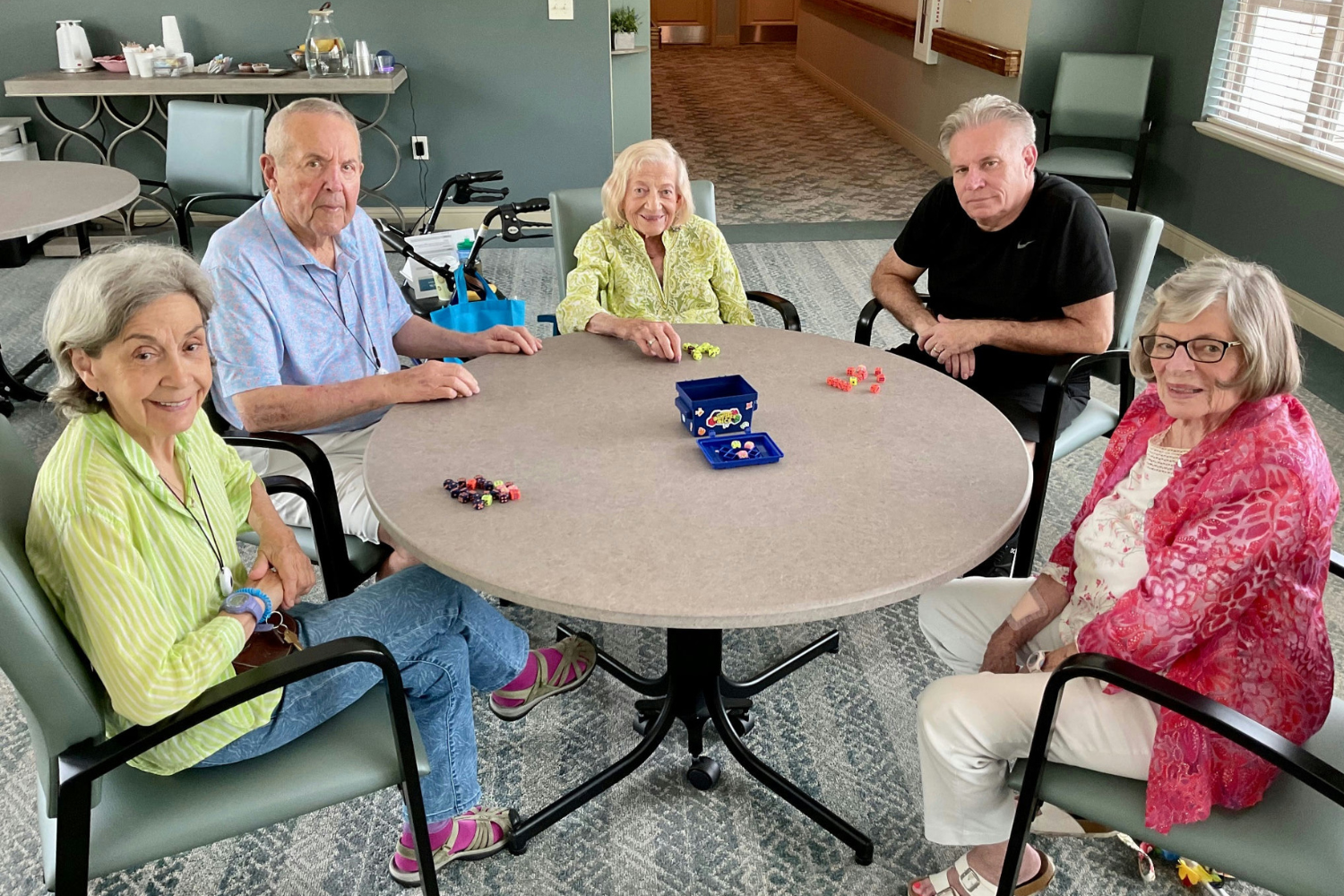 Residents gather around a round table for a friendly dice game at this senior living community in Lakeway, TX, enjoying a fun and stimulating social activity that fosters connection at Arbor Terrace.
