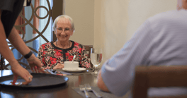 A resident enjoying a warm moment at the dining table at Arbor Terrace Prince William Commons, reflecting the attentive and caring service found in this assisted living Woodbridge, VA community.