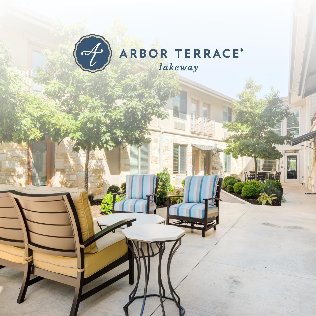 Outdoor patio seating area at Arbor Terrace Lakeway, featuring cushioned lounge chairs and a small side table surrounded by mature trees and a stone building facade.Cover-page-001