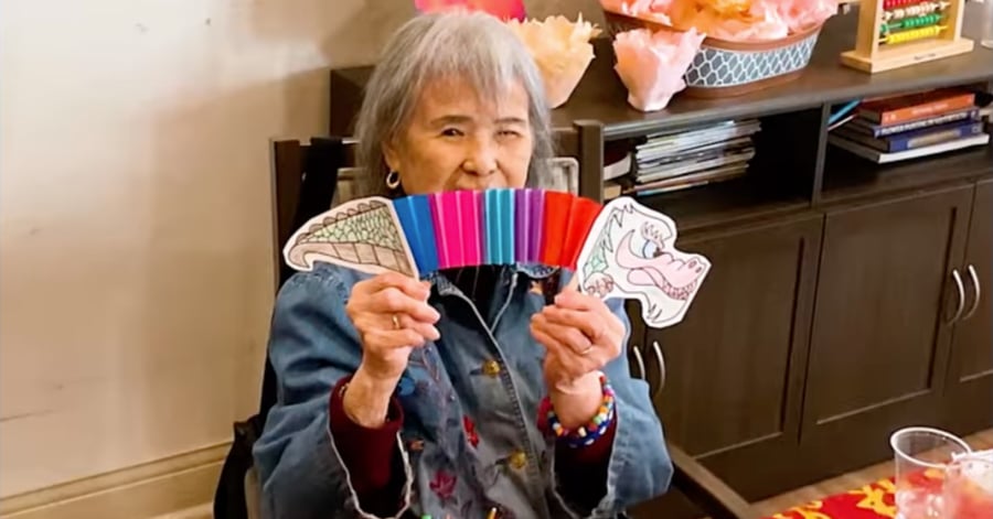 A cheerful older adult holds up colorful craft cutouts and markers at Arbor Terrace Lakeway, beaming with joy — celebrating joyful senior living Lakeway Texas.