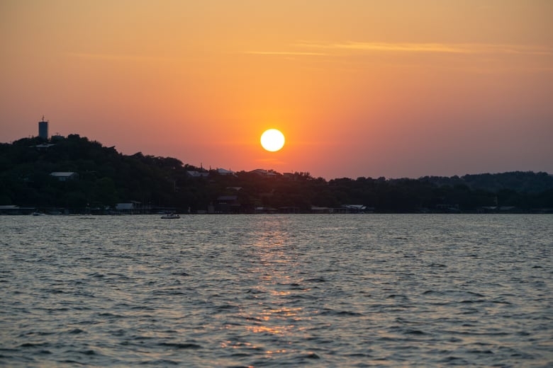 A warm sunset over the Lake Travis waterfront in Hudson Bend, a scenic peninsula community near Arbor Terrace Lakeway senior living in Lakeway, TX.