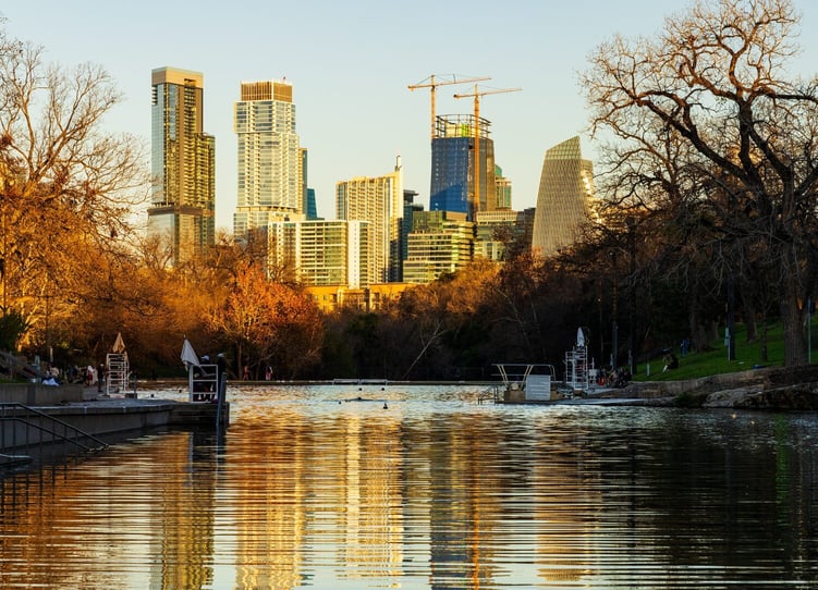 A tree-framed view of the West Austin skyline at dusk, reflecting the vibrant urban energy just a short drive from Arbor Terrace Lakeway in Lakeway, TX.