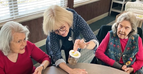 A staff member engages two residents in a hands-on activity at Arbor Terrace Lakeway, showcasing the thoughtful and personalized programming offered at this memory care community in Lakeway, TX.