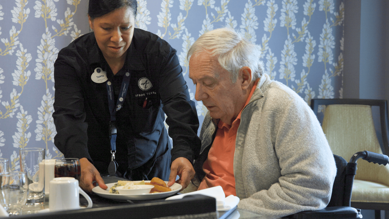  Two residents share a joyful toast over a beautifully plated meal in the dining room at Arbor Terrace Waugh Chapel, capturing the warm, resort-style dining experience and vibrant social atmosphere that define senior living at this assisted living community in Gambrills, MD.
