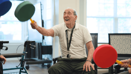 Senior resident playing games with a paddle and ball during a fitness activity