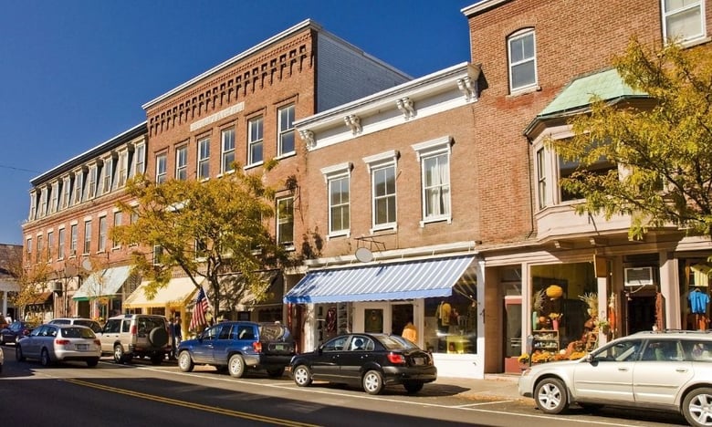  Tree-lined brick storefronts along a sunny street in Middletown, a well-rooted community within easy reach of assisted living in Shrewsbury, NJ.