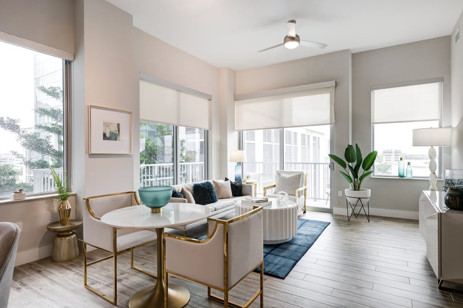 A beautifully appointed living room in an independent living apartment at Mirabelle features gold-accented furniture, soft natural light, and balcony views, reflecting the refined lifestyle of senior living in Miami, FL.