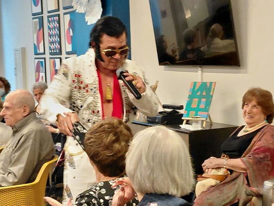 Residents enjoying a lively Elvis tribute performance during a happy hour event at Mirabelle Dadeland, capturing the vibrant social spirit of active senior living in Miami, FL.