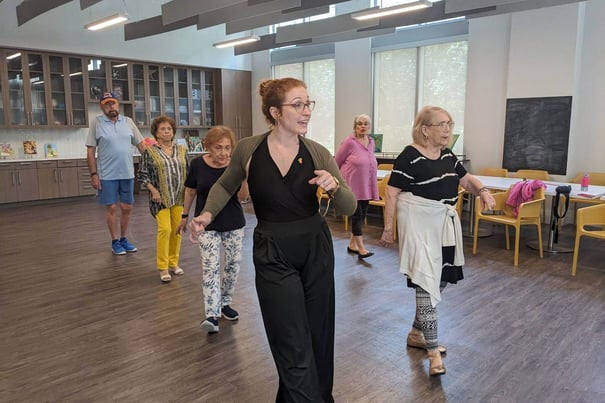 An instructor leads residents in a dance class in a bright activity room, highlighting the engaging life enrichment programs at this senior living community in Miami, FL.