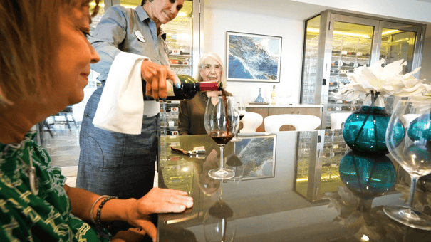 A staff member pours wine for residents at an elegantly styled bar at Mirabelle, capturing the resort-style assisted living experience in Miami, FL where attentive service and refined amenities are part of daily life.