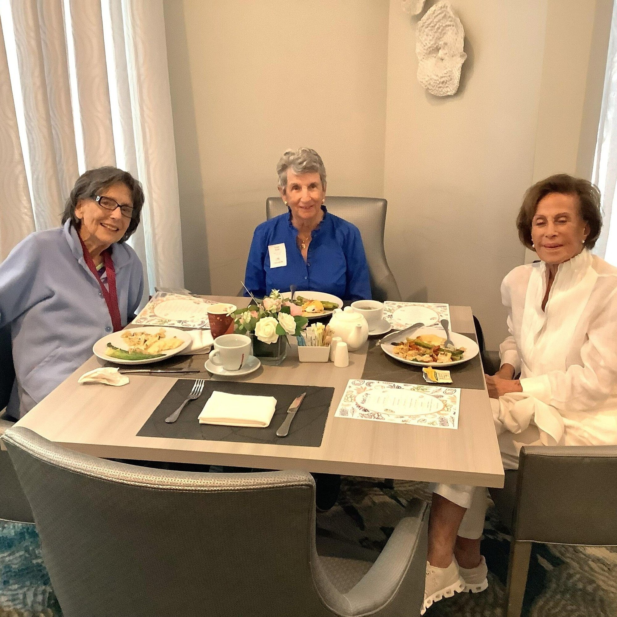 Residentes comparten un emotivo momento alrededor de una mesa festiva en Mirabelle, comunidad de senior living en South Miami, FL, celebrando una ocasión especial juntos.