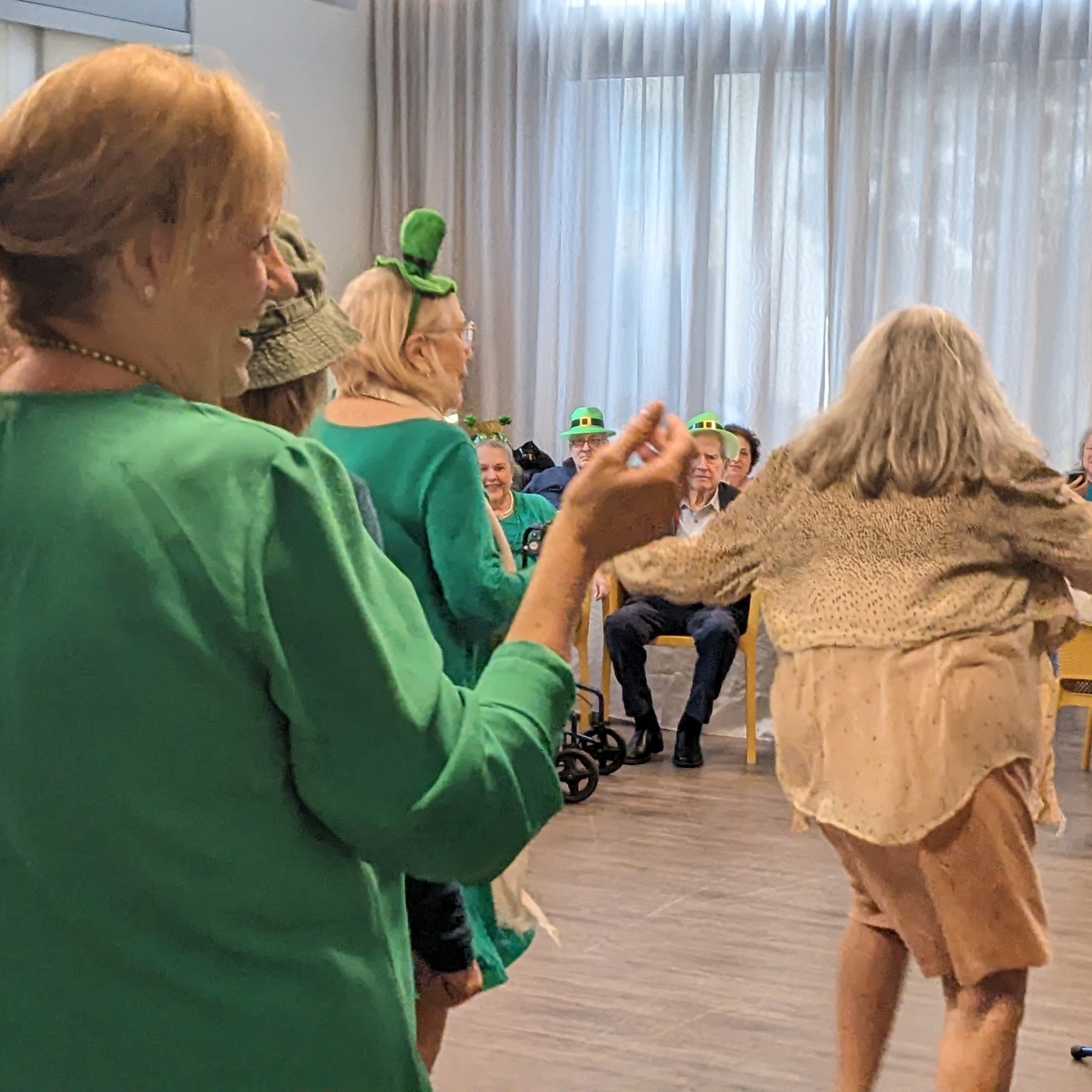 Residentes sonríen y bailan juntos en un salón de actividades de Mirabelle, comunidad de senior living en Miami, FL, durante una celebración especial llena de alegría.