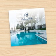 Portada de un folleto que muestra una piscina con área de descanso blanca y un edificio moderno de fondo, ideal para la vida sénior estilo resort en Miami, FL.