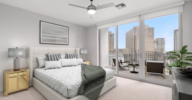 A bright, well-appointed apartment bedroom featuring large floor-to-ceiling windows with sweeping city views, showcasing the spacious senior apartments available in Miami, FL at Mirabelle Dadeland.