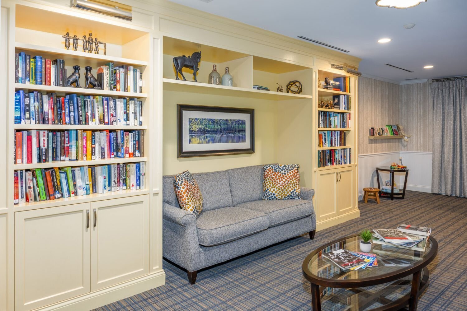a library with a couch and many bookshelves in Arbor Terrace Monmouth