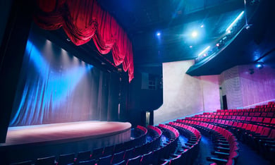 A grand theater interior with red curtains and stage lighting, representing the arts and cultural venues near this assisted living Shrewsbury NJ community — close to the Red Bank arts district enjoyed by senior living Shrewsbury NJ residents.