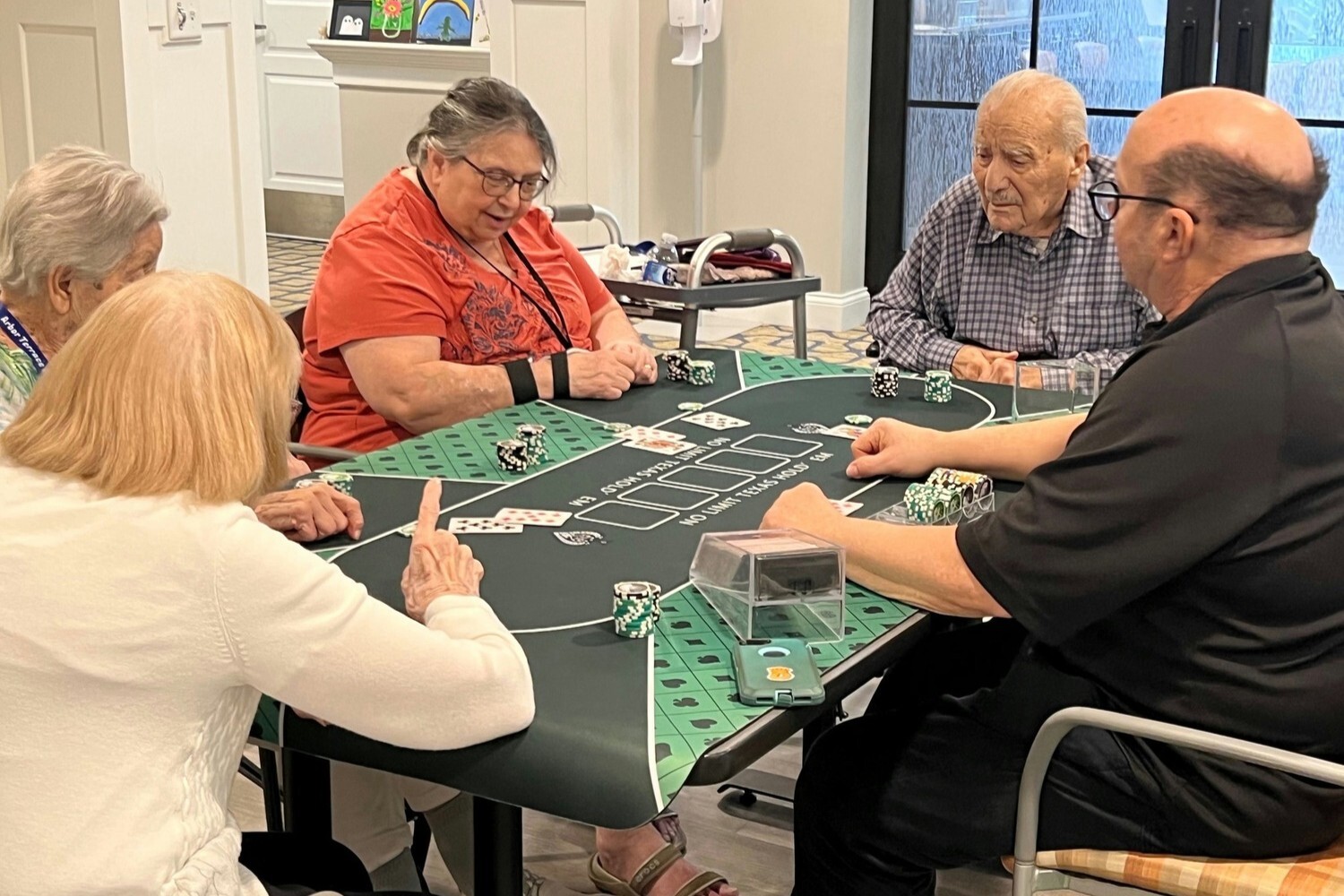 Residents enjoy a lively card game around a casino-style table at Arbor Terrace Monmouth, capturing the engaging lifestyle of senior living in Shrewsbury, NJ.