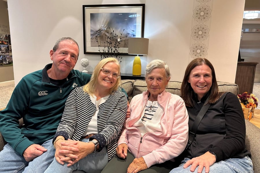 Four people smile warmly together on a couch in a bright, welcoming lounge at Arbor Terrace Morris Plains, capturing the warm sense of community found in personalized assisted living in Morris Plains, NJ.