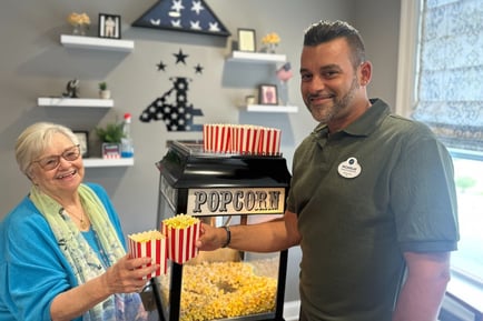 A resident receives fresh popcorn from a team member during a popcorn bar social at Arbor Terrace Mountainside