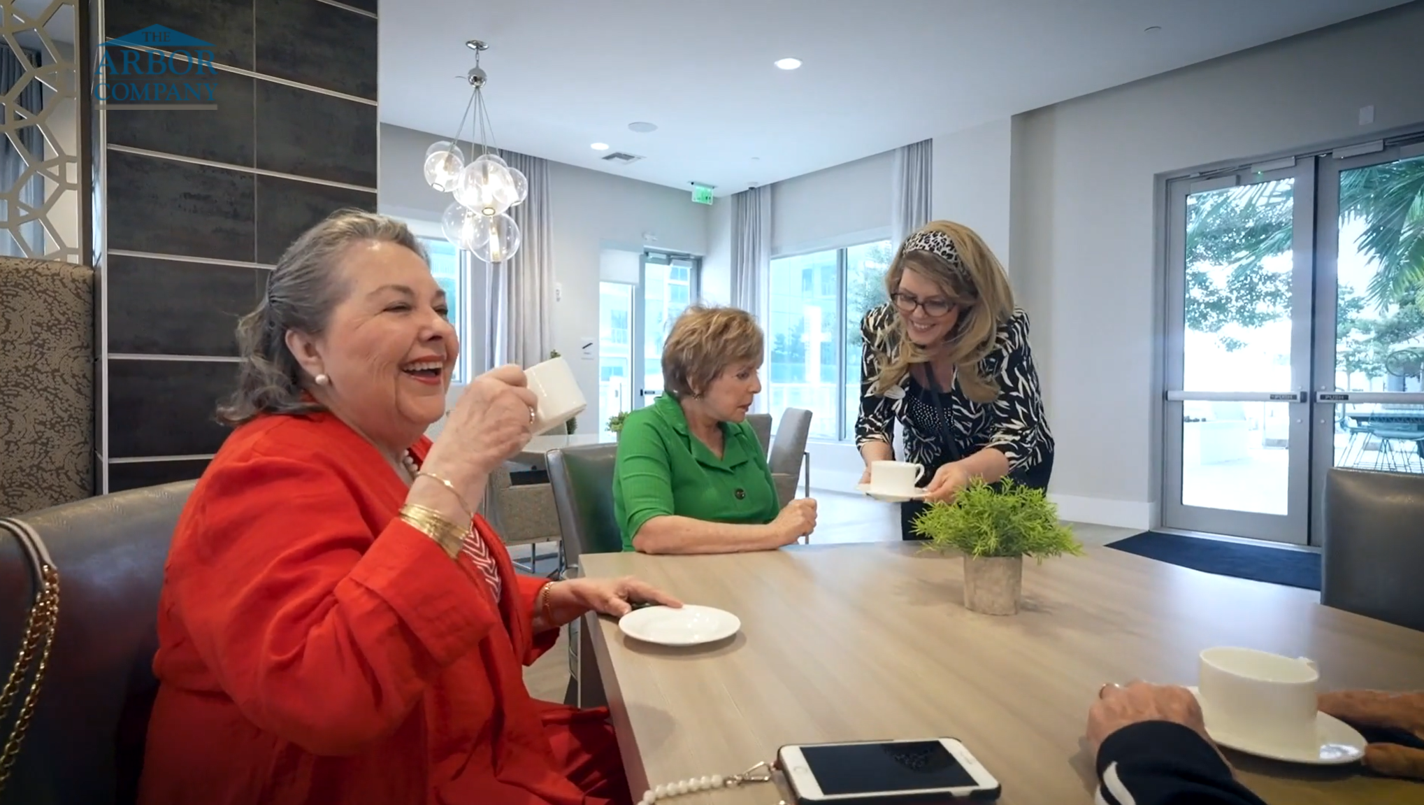 a staff bringing tea to a senior lady while another lady enjoys her tea