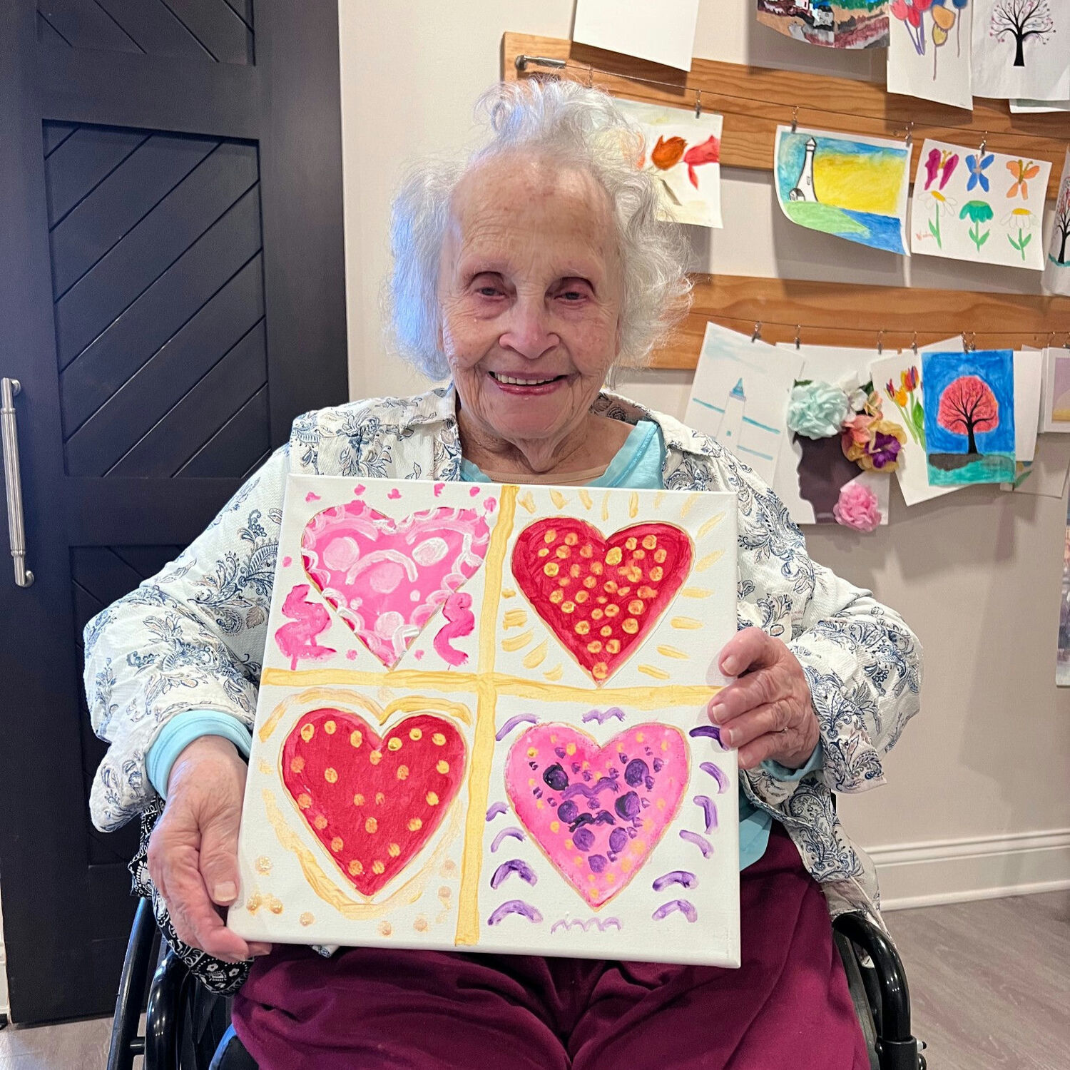 A senior lady proudly showing her Valentine's artwork from an art class at a senior living community in Norwood, NJ
