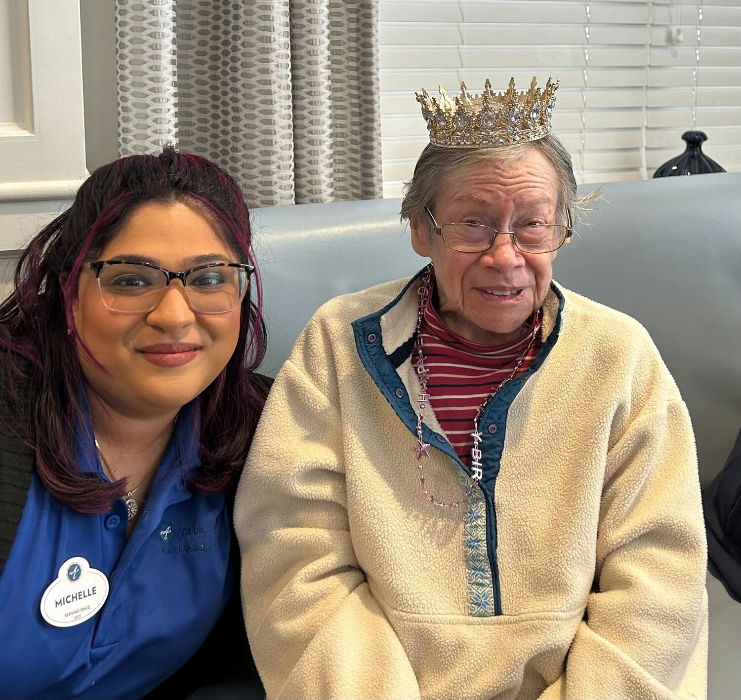 a senior lady wearing a crown and smiling together with a staff member of a senior living community in Norwood, NJ