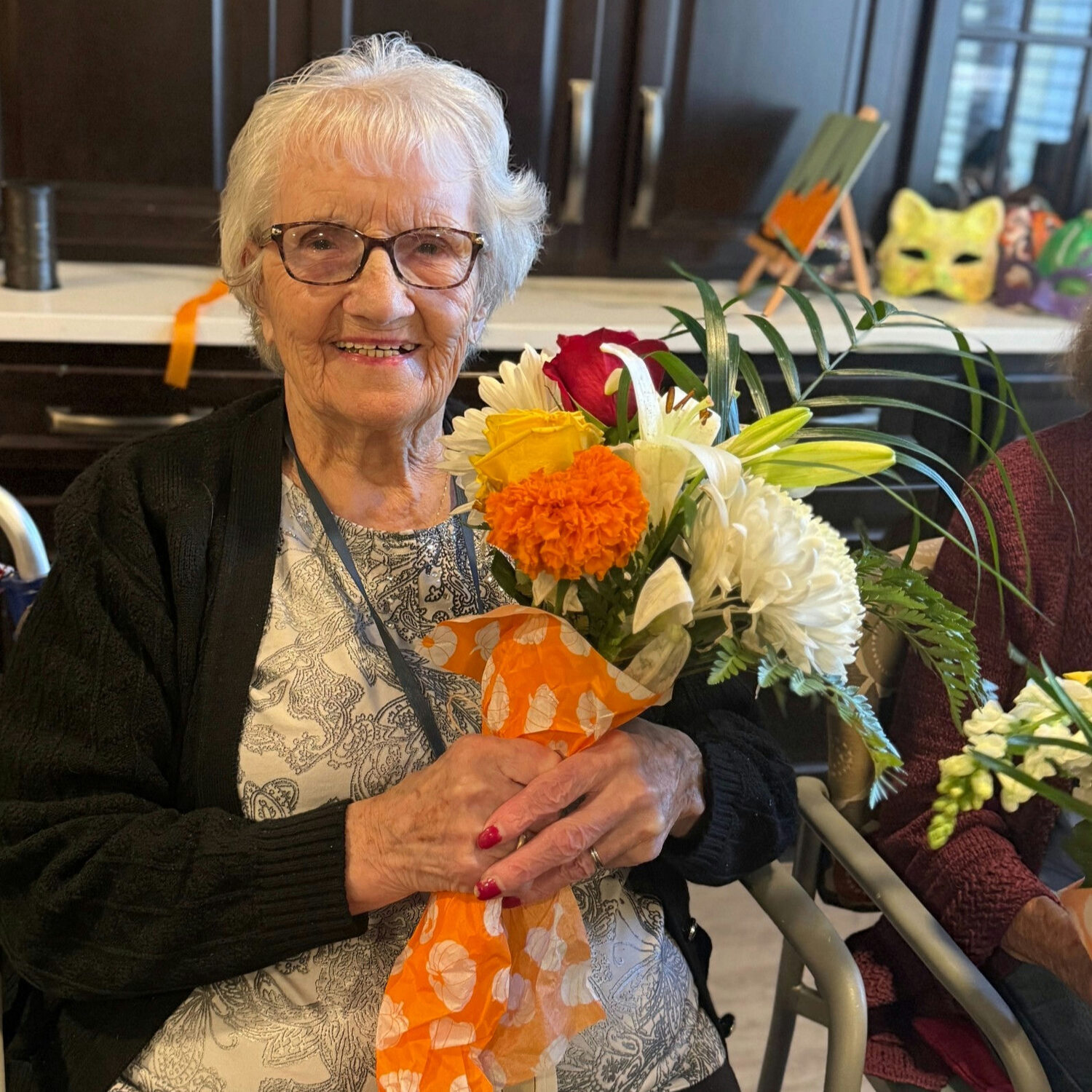 A senior lady hugging a bouquet of flowers during a springtime activity at a senior living community in Norwood, NJ